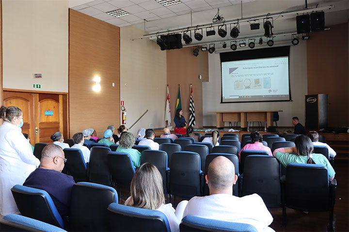#ParaTodosVerem Fotografia panorâmica do anfiteatro do HSPM, na qual aparecem os participantes, sentados, assistindo à palestra.