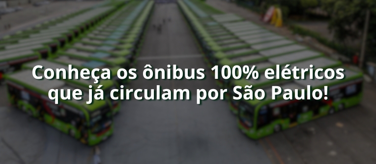 Imagem com fundo desfocado mostrando uma grande frota de ônibus elétricos verdes estacionados em um pátio. Ao centro da imagem, em destaque, aparece o texto em branco: “Conheça os ônibus 100% elétricos que já circulam por São Paulo!”