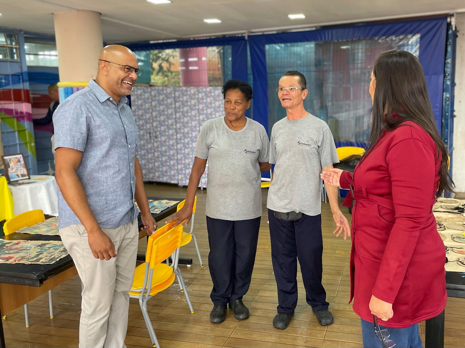 #PraTodosVerem: Subprefeito Ozziel Souza ao lado de três munícipes, sendo uma mulher e um homem, ambos idosos e vestindo um uniforme na cor cinza, e uma mulher mais jovem de casaco vermelho. Ozziel usa uma camisa social na cor azul.